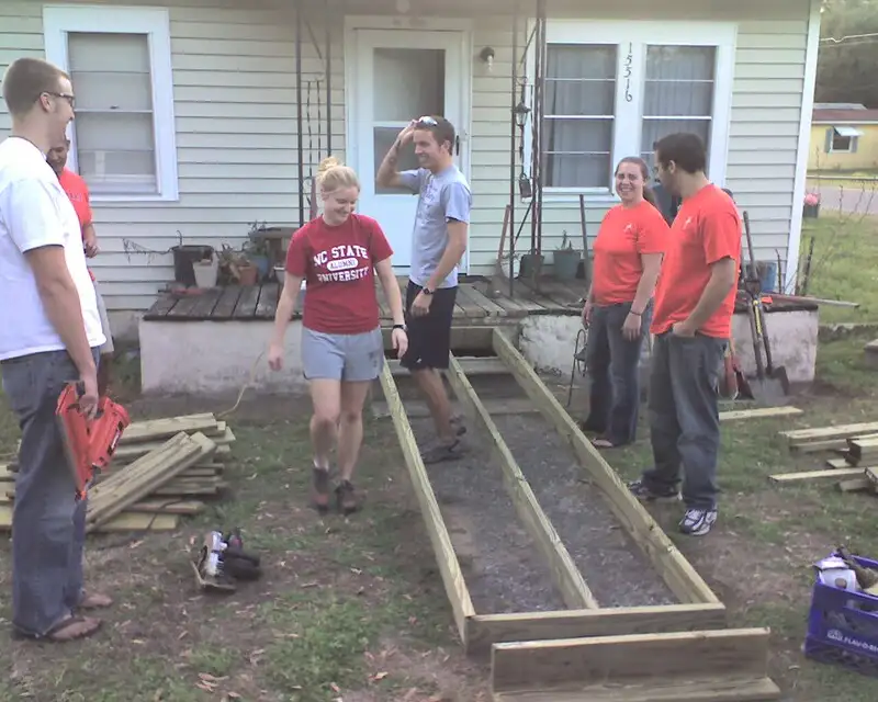 A group of volunteers are relaxing after framing in a wooden ramp.