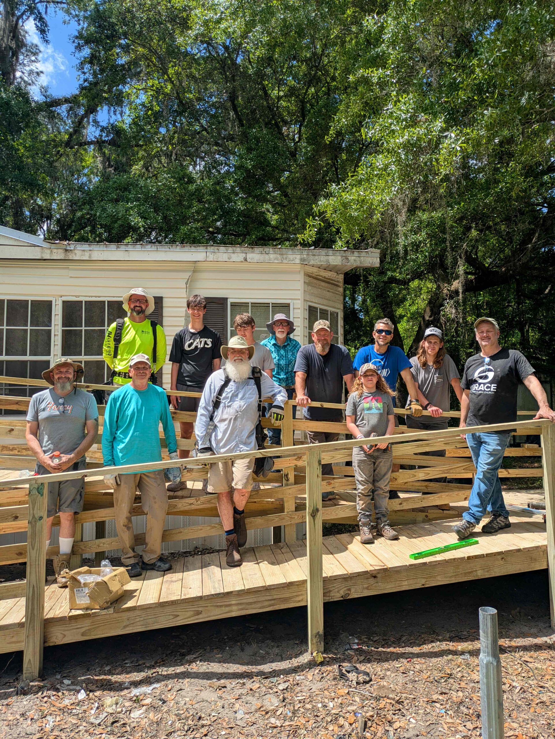 Four volunteers are finishing their construction of a wooden staircase by adding handrails to it.